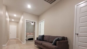 En hall med en brun soffa, vita dörrar och en takfläkt.