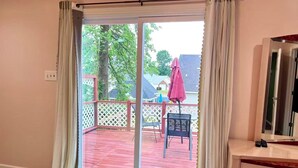 A room with a sliding glass door leading to an outdoor deck with a red wooden floor, a white lattice fence, and a pink umbrella. - Charming Home with Prime Augusta Location - Walk to Augusta National! (Augusta)
