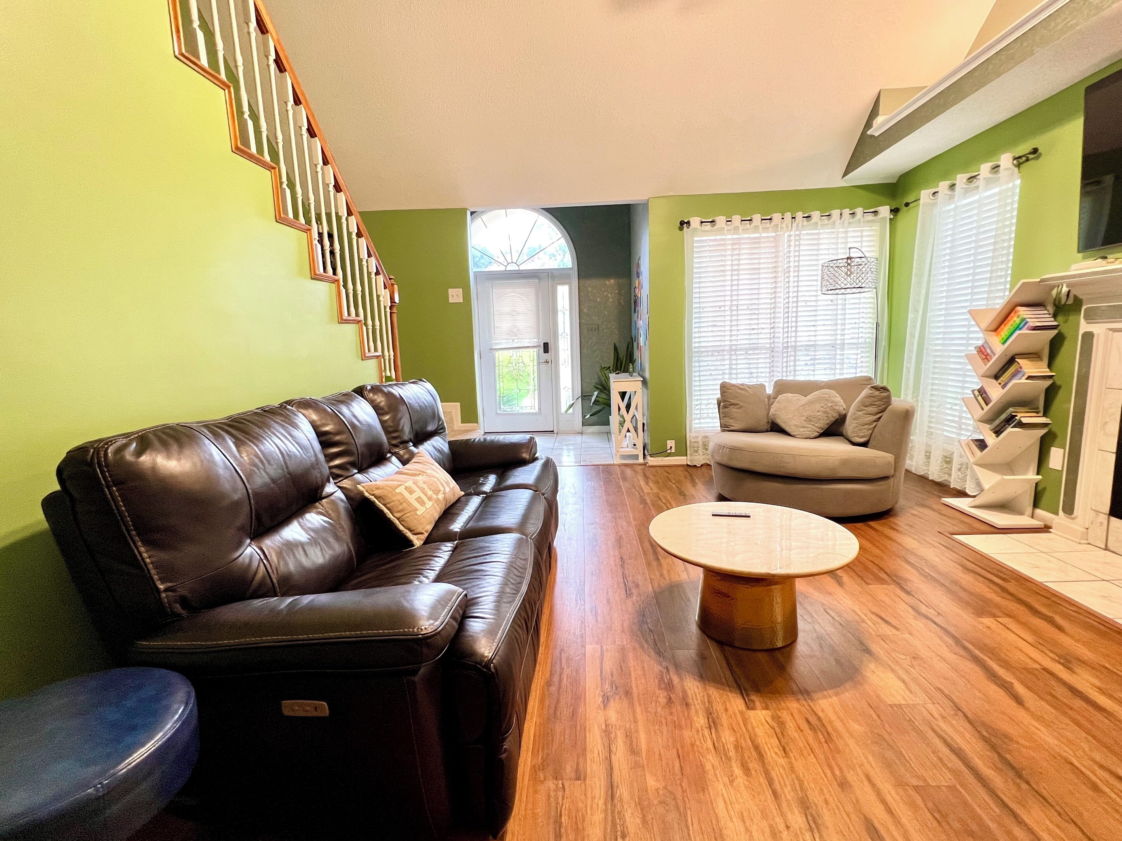 A living room with a brown leather sofa, a round coffee table, a beige sofa, and a bookshelf.