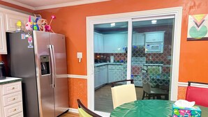 A kitchen with a refrigerator, cabinets, a dining table with chairs, and a sliding glass door leading to an adjacent room. - Charming Home with Prime Augusta Location - Walk to Augusta National! (Augusta)