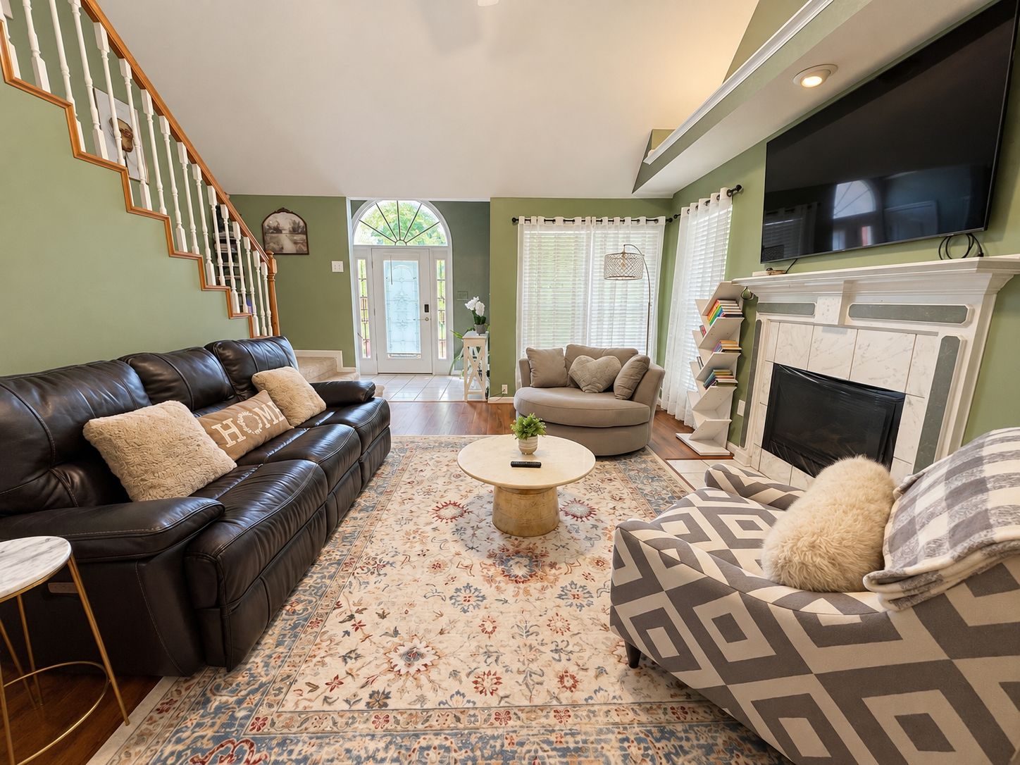 A living room with a black leather sofa, a beige sofa, a patterned rug, a coffee table, and a fireplace.
