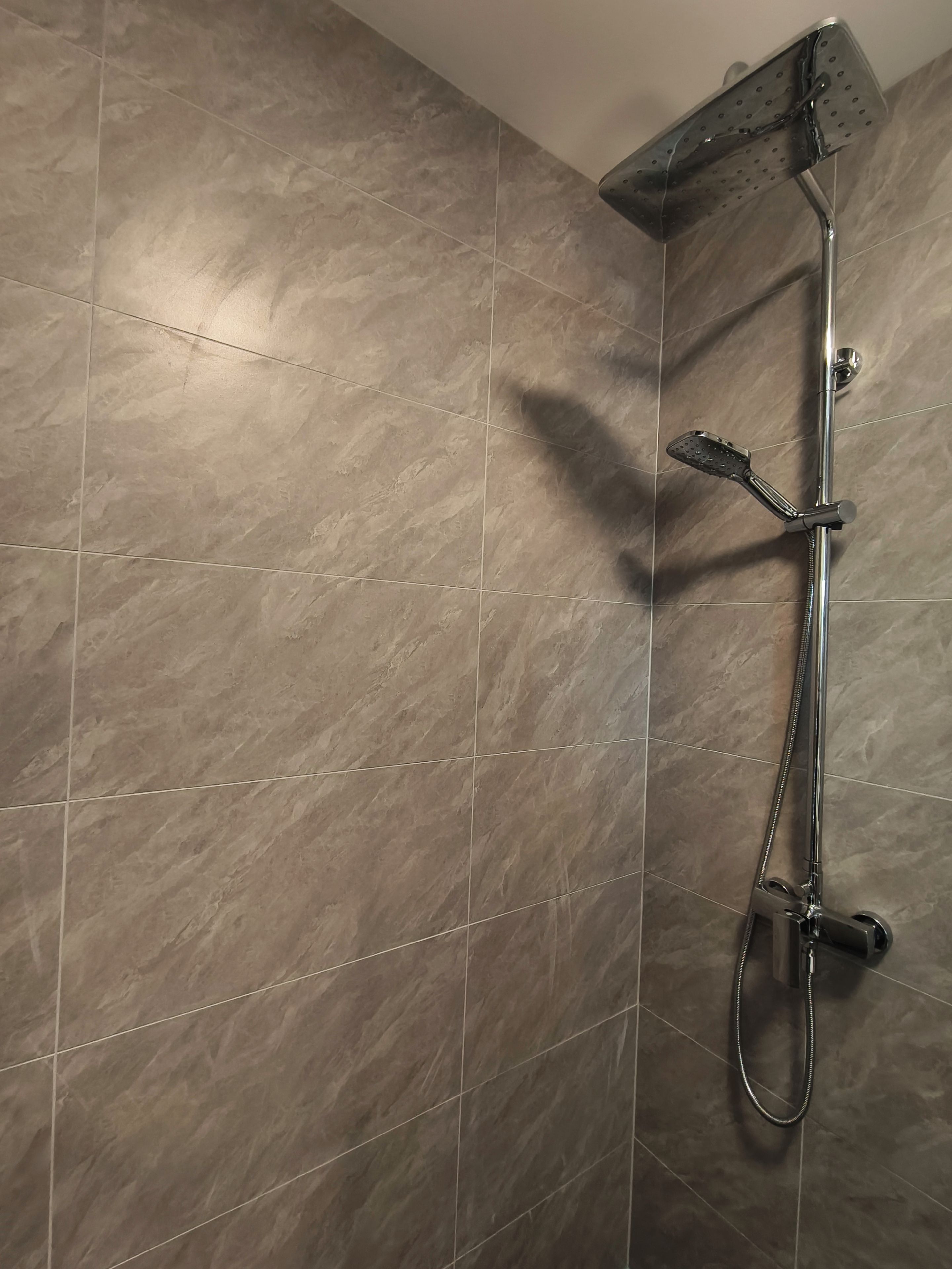 A shower with a handheld showerhead and a fixed overhead showerhead.