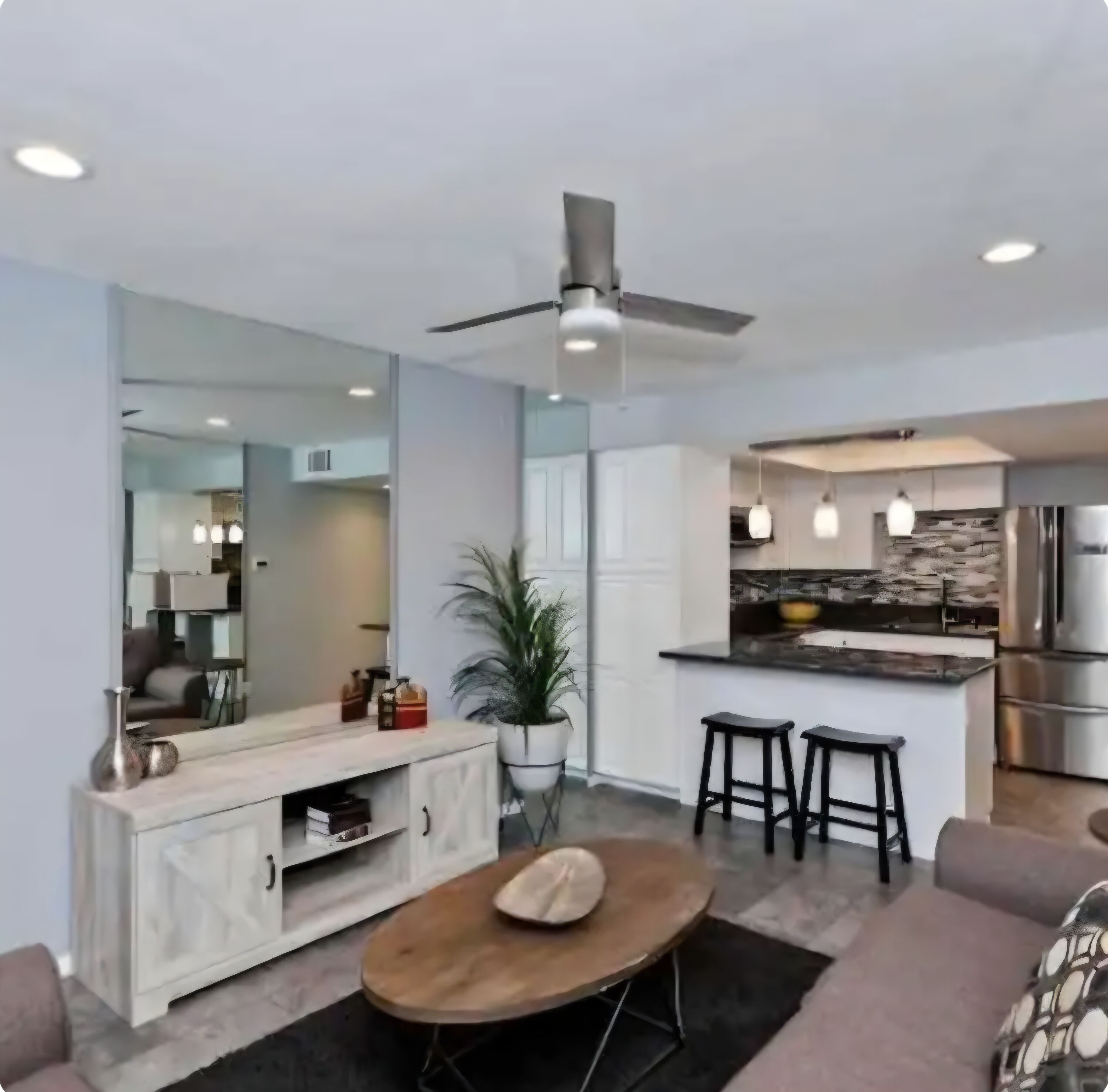 A modern living room with a wooden coffee table, a sofa, and a dining area with a kitchen in the background.