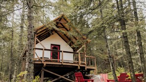 A wooden cabin with a balcony, surrounded by trees.