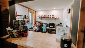 A reception area with a wooden counter, a black trash bin with a paw print, and a shelf with red containers.