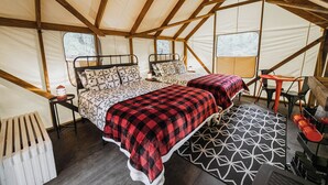 A tent with two beds, a table, chairs, and a radiator.
