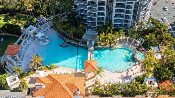 Et resort med en stor central pool, flere balkoner og frodig beplantning.