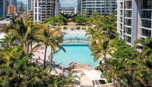 A resort with a central pool surrounded by palm trees and high-rise buildings in the background. - 2BRM Panoramic Views - Chevron Renaissance (Gold Coast)