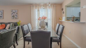 A dining area with a glass table, chairs, a vase with flowers, and a 'No Smoking' sign. - The Sunny House Family Retreat Near IMG & Anna Maria: A Dedicated Workspace (Bradenton)