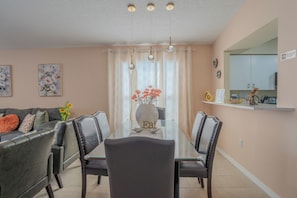 A dining area with a glass table, chairs, a vase with flowers, and a 'No Smoking' sign. - The Sunny House (Bradenton)