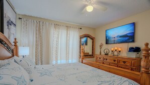 A bedroom with a bed, a dresser, a television, a mirror, and a ceiling fan. - The Sunny House Family Retreat Near IMG & Anna Maria: A Dedicated Workspace (Bradenton)