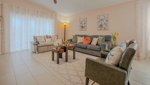 A living room with a sofa, armchairs, a coffee table, a ceiling fan, and a lamp. - The Sunny House Family Retreat Near IMG & Anna Maria: A Dedicated Workspace (Bradenton)