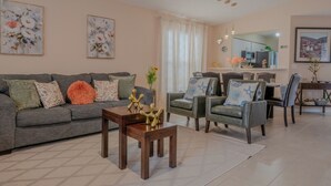 Uma sala de estar com sofá, cadeiras, mesa de centro e obras de arte nas paredes.