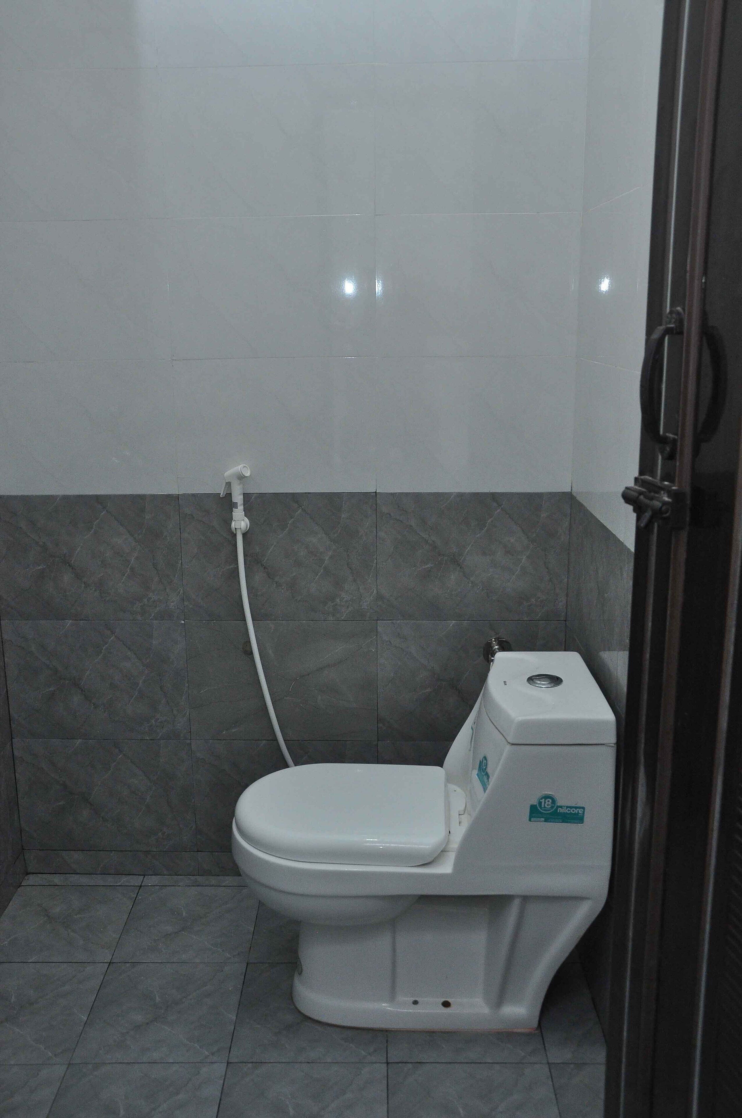 Ein Badezimmer mit Toilette, Dusche und Wandarmatur.