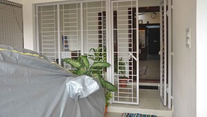 A room with a sliding glass door leading to a balcony, a covered outdoor area, and a potted plant. - Chithu Home Stay in Temple City (Kumbakonam)