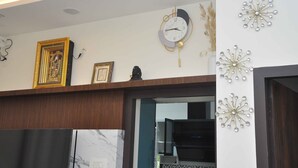 A modern kitchen with a marble countertop, a built-in oven, and decorative wall clocks. - Chithu Home Stay in Temple City (Kumbakonam)