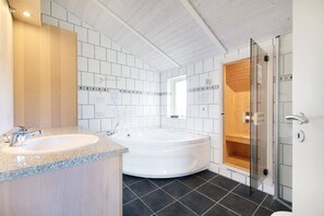 A modern bathroom with a sink, bathtub, and shower. - Holiday home with a spa and sauna by the water (Rudkøbing)