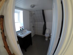 A bathroom with a white sink, a toilet, and a shower. - Apartment in the first row 180 degree sea wiew (Rudkøbing)