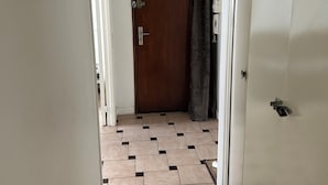 A hallway with a patterned floor, a wooden door, and a curtain. - Lovely Family Stay - Two  Bedroom - Right Edge of Paris (Clichy)