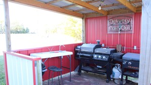 Un área de barbacoa al aire libre con una parrilla, un lavamanos y un taburete.