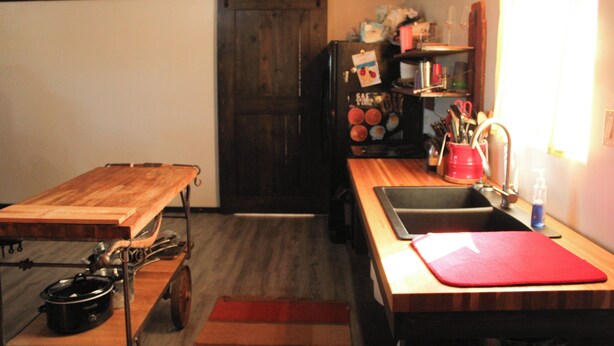 Una cocina compacta con una mesa de madera, un lavamanos y un refrigerador.