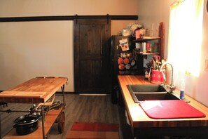 Eine kleine Küche mit Holztisch, Spüle und Kühlschrank.