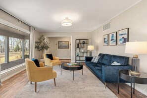 A modern living room with a sofa, armchairs, a coffee table, and a lamp.