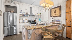 A kitchen with a stainless steel refrigerator, wooden island, and a chandelier. - Romantic Dragonfly Cottage with Deeded Beach Access! Meticulously Maintained! (Orange Beach)