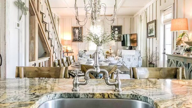 A kitchen with a granite countertop, stainless steel sink, and a chandelier. - Romantic Dragonfly Cottage with Deeded Beach Access! Meticulously Maintained! (Orange Beach)
