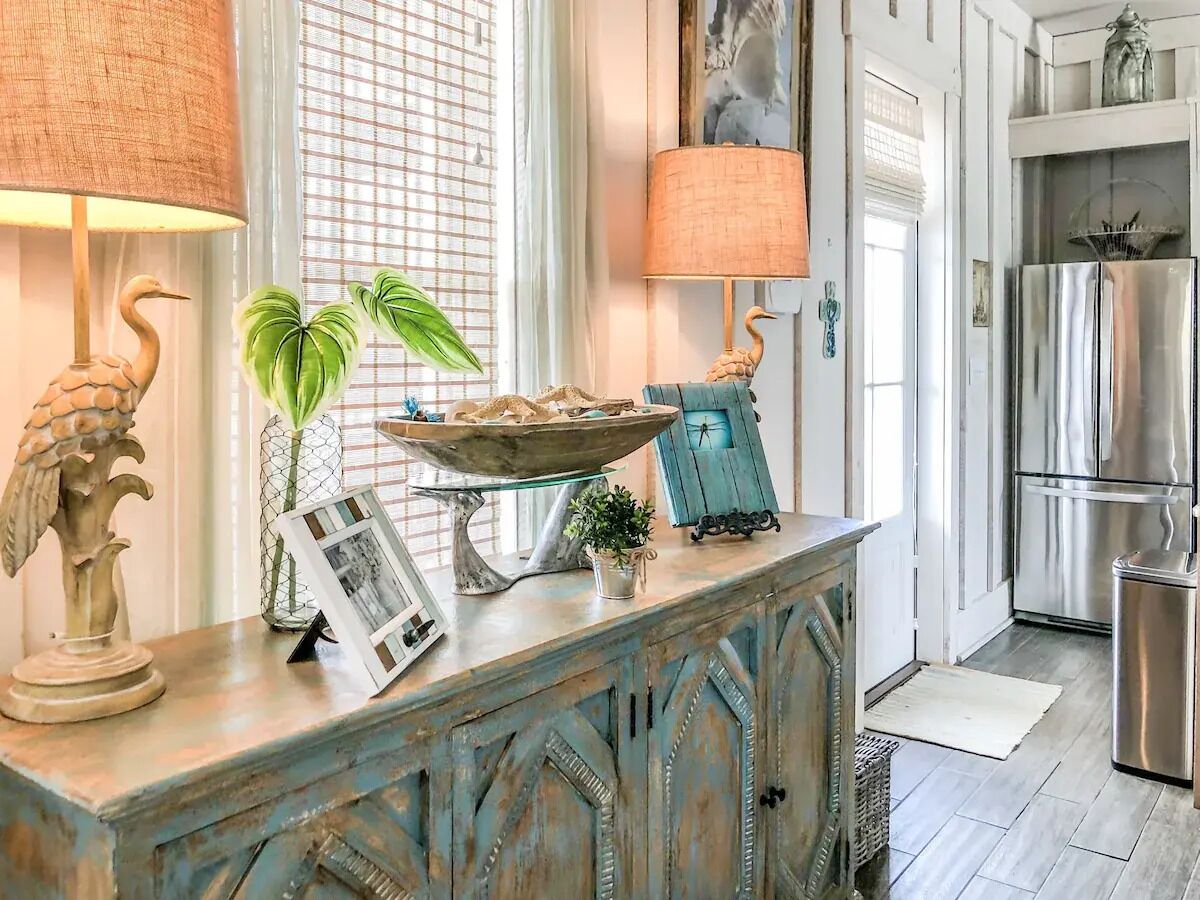A kitchen with a rustic wooden island, a stainless steel refrigerator, and a window with blinds.