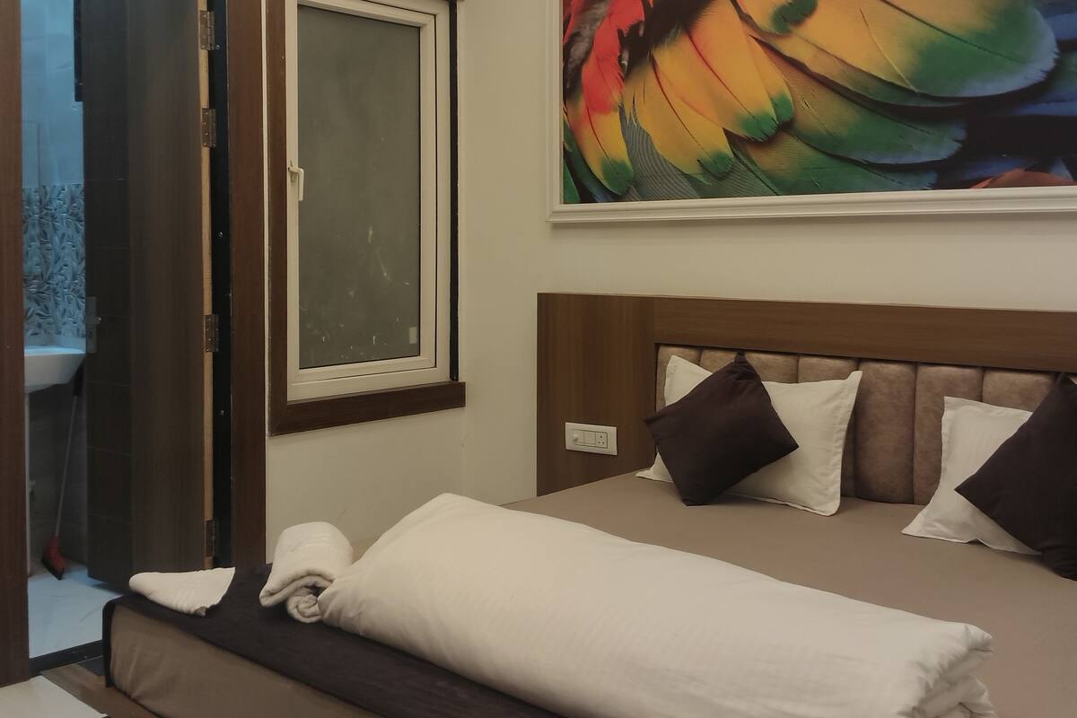 Une chambre d’hôtel avec un lit, une grande fenêtre et un tableau représentant un oiseau.