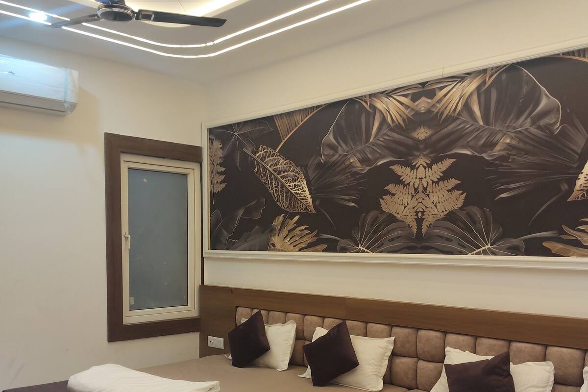 Une chambre moderne avec un grand lit, un ventilateur de plafond et un climatiseur fixé au mur.