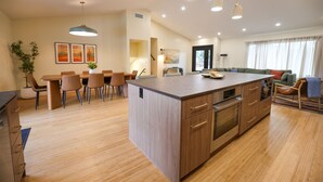 Una cucina moderna con isola centrale, mobili in legno e illuminazione a sospensione.