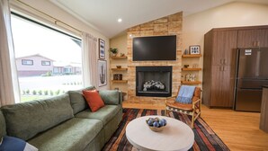 Uma sala de estar com sofá, lareira, televisão e uma área de cozinha.