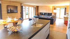 A modern kitchen with a central island, wooden cabinetry, and a large window providing natural light.