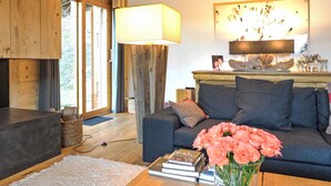 A modern living room with a dark grey sofa, a wooden coffee table, and a vase of pink flowers.