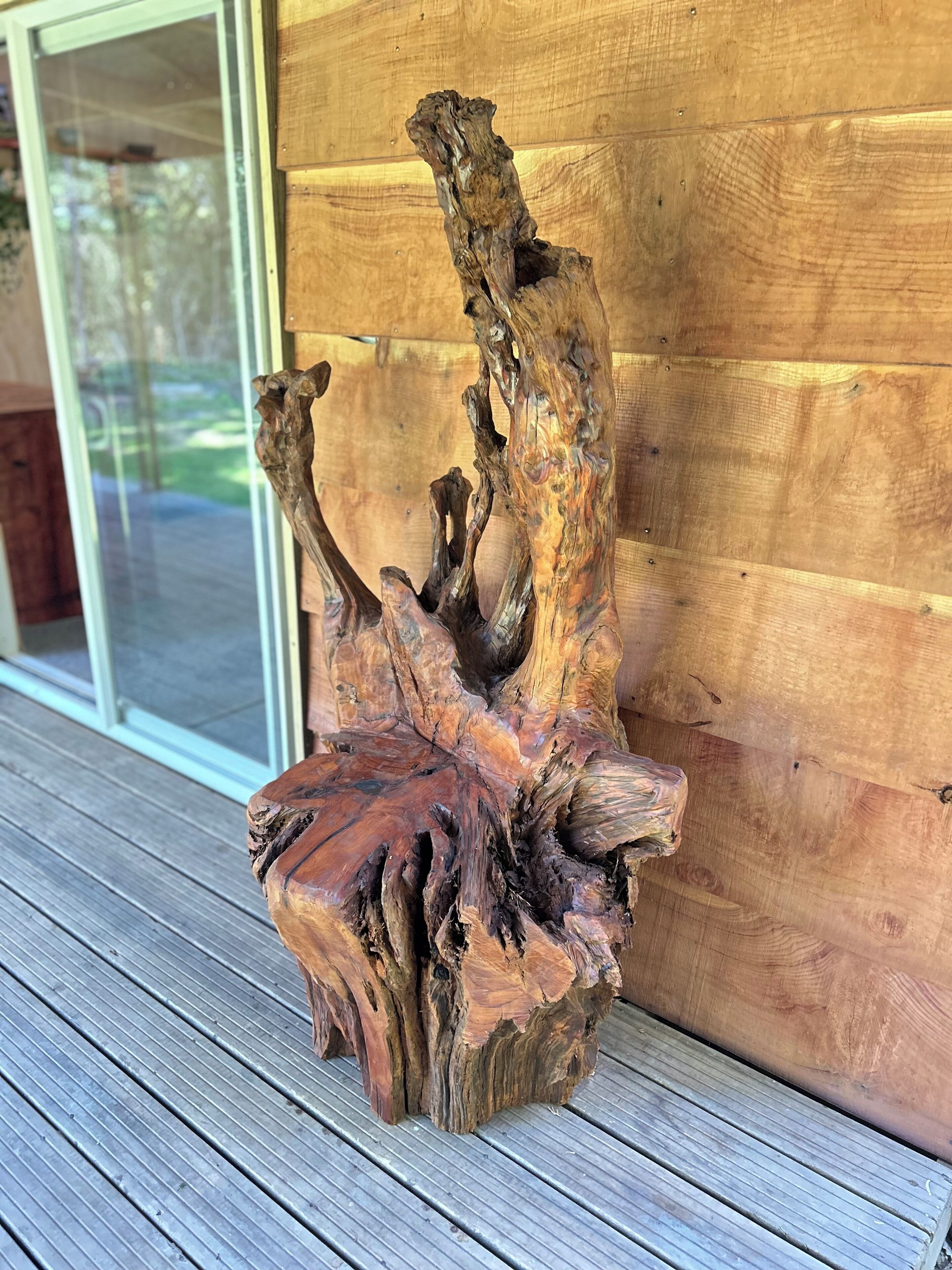 Een houten sculptuur op een terras.