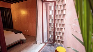 A bedroom with a bed, a window with a view, and a door leading to a balcony. - Hotel Casa de las Abuelas (Guanajuato)