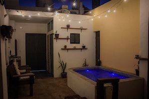 A small outdoor pool area with string lights, a chair, and shelves with plants. - Descanso familiar o romantico con plunge pool (Mazatlán)