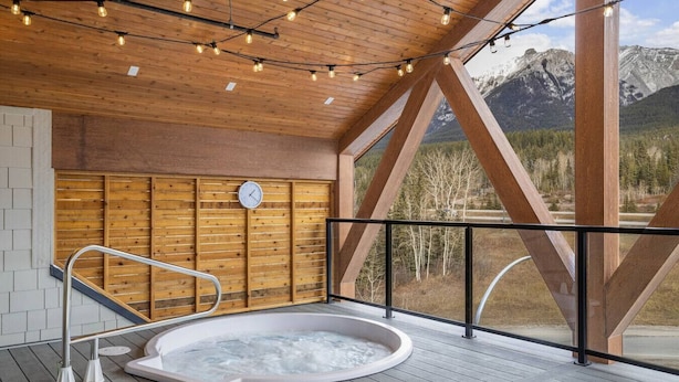 A hot tub on a wooden deck with a view of mountains. - 4BR Getaway with MTN View, Balcony Near DT & Banff! (Canmore)