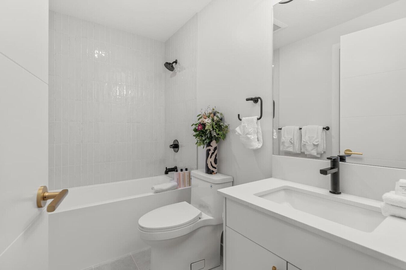 A modern bathroom with a bathtub, toilet, and vanity.