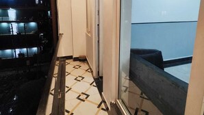A narrow corridor with a patterned floor, a glass door leading to a balcony, and a ceiling light. - BLACKSTORM RESIDENCY HOTEL (Greater Noida)
