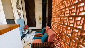 A modern interior with a patterned floor, a wooden reception desk, a sofa with cushions, and a decorative wall with geometric patterns. - BLACKSTORM RESIDENCY HOTEL (Greater Noida)