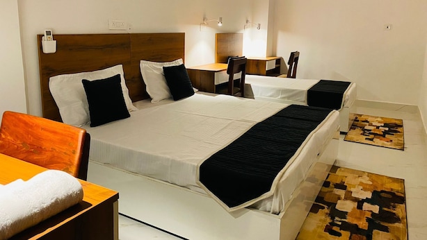 A hotel room with a large bed, bedside tables, a desk, and a chair. - BLACKSTORM RESIDENCY HOTEL (Greater Noida)