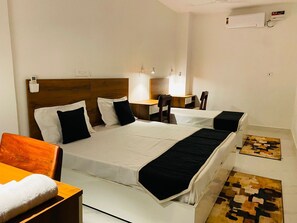 Een hotelkamer met een groot bed, nachtkastjes, een bureau en een stoel.