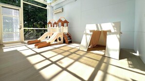 A room with a wooden playset, including a slide and climbing structure, and a tent-like playhouse. - dream castle (Wujie)