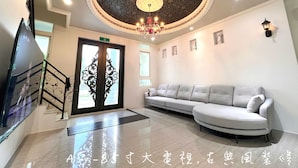A hotel lobby with a chandelier, a sofa, a staircase, and a door with intricate designs. - dream castle (Wujie)