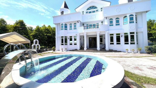 A large, white, two-story building with a swimming pool in front. - dream castle (Wujie)