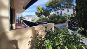 A balcony with a view of trees and a distant cityscape. - 2 rooms, WIFI, sea view, garden, private parking (ST MANDRIER SUR MER)