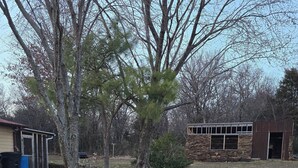 Un camino de grava que conduce a un edificio de piedra con techo metálico y puerta de cristal.